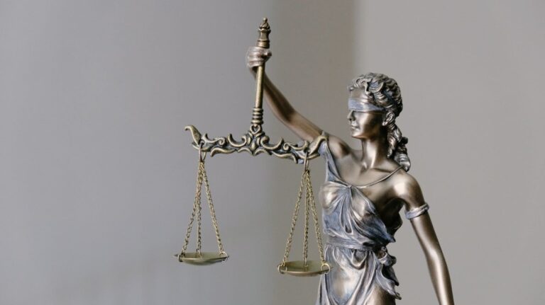 Une statue en bronze représente une femme les yeux bandés tenant dans sa main droite la balance de la Justice