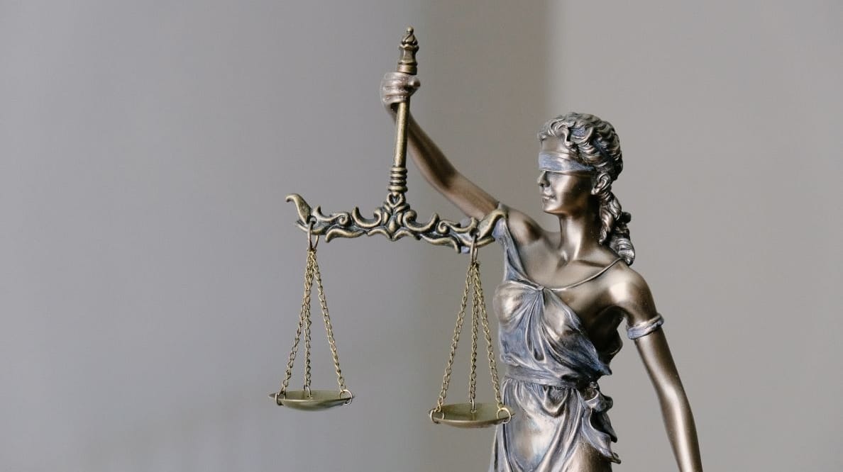 Une statue en bronze représente une femme les yeux bandés tenant dans sa main droite la balance de la Justice