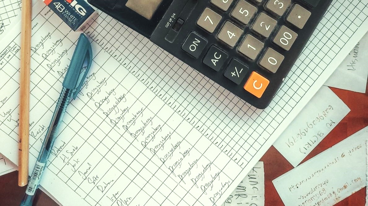 Une calculatrice est posée parmi des feuilles où des calculs complexes sont écrits