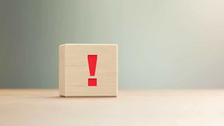 Un cube en bois avec un point d'exclamation est posé sur une surface plane