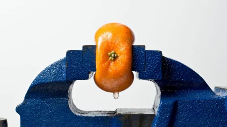 Une orange pressée par un étau