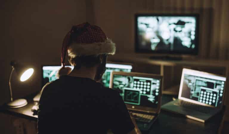 Hacker devant plusieurs écrans d'ordinateur avec un bonnet de Noël