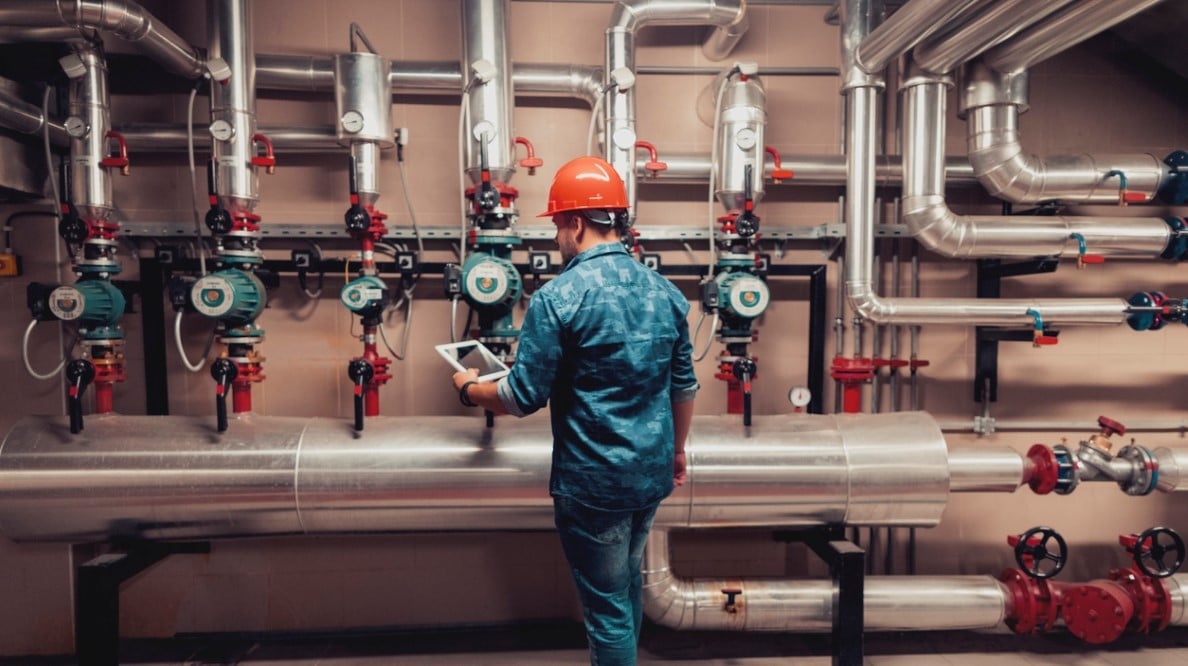 Un technicien opère des tuyaux de conduites industrielles en utilisant une tablette connecté.