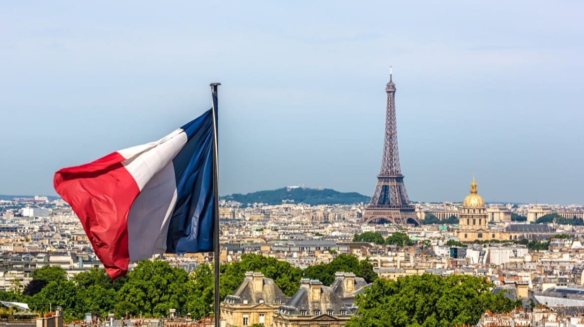 Une photo de Paris et la Tour Eiffel avec un drapeau français en avant-plan.