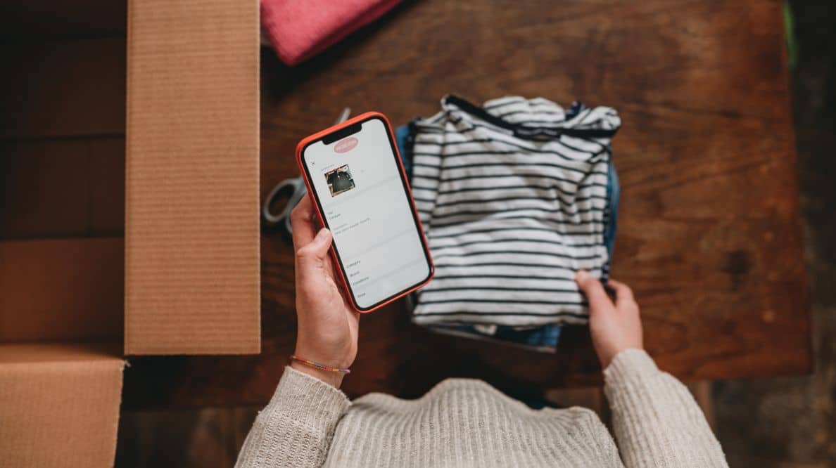 Une personne en train de photographier des vêtements avec son téléphone portable avant de les mettre en vente en ligne.