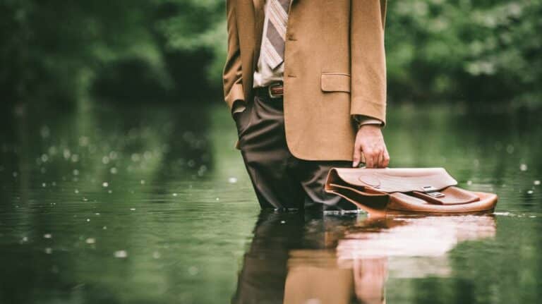 Un homme en costume-cravate les jambes dans l'eau à cause d'une inondation