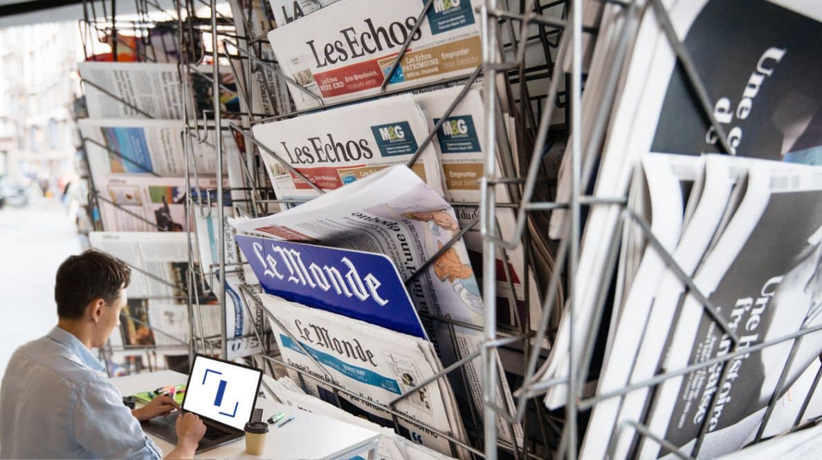 Un homme travaillant sur son ordinateur devant un kiosque à journaux
