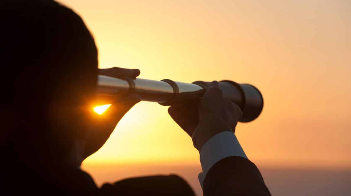 Une personne regardant un coucher de soleil à travers une longue vue