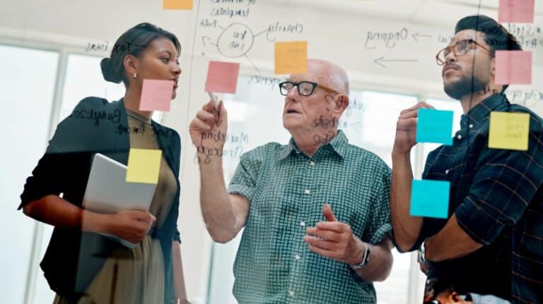 Un senior travaillant avec deux plus jeunes personnes