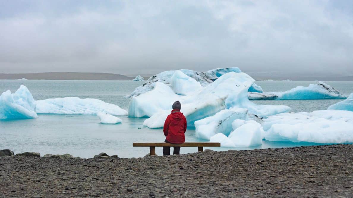 Une jeune personne assise sur un banc face à des glaciers