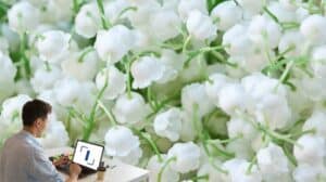 Un homme travaillant sur son ordinateur devant du muguet